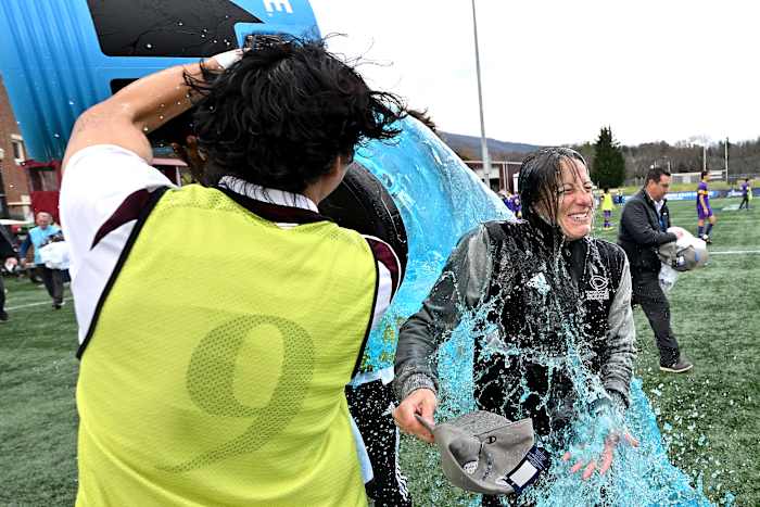 A player in a yellow pinnie dumps blue Powerade over coach Julianne Sitch